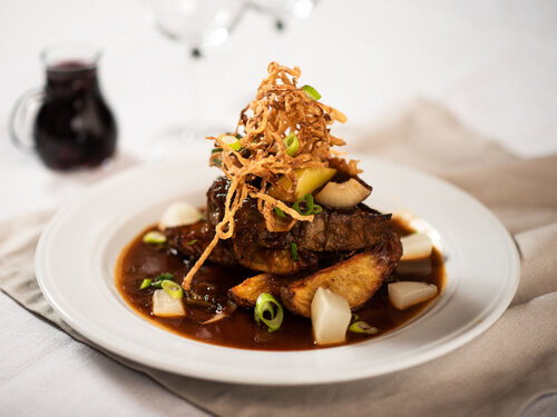 "Chefs Zwiebelrostbraten" Rosa Schnitte vom Beiried mit Erdäpfelspalten, Röstzwiebel und Senfgurke